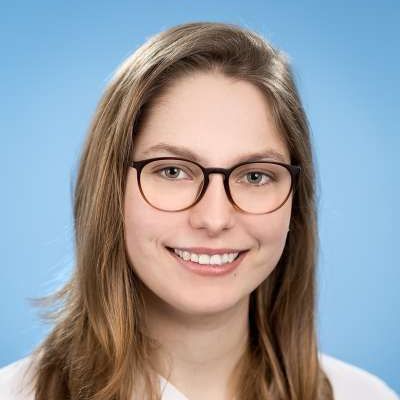 Die Frau trägt eine Brille und lächelt in die Kamera.