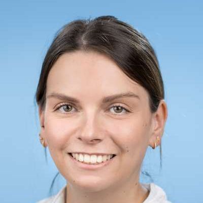 Eine Nahaufnahme des lächelnden Frauengesichts vor blauem Hintergrund.