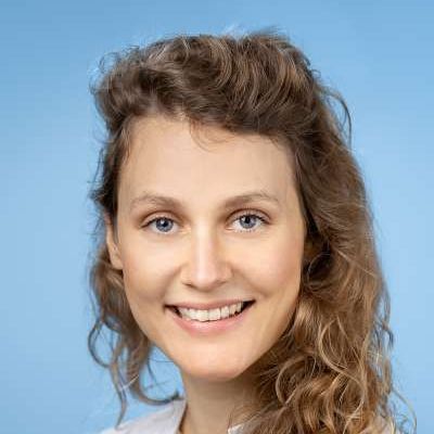 Eine Frau mit lockigem Haar lächelt in die Kamera.