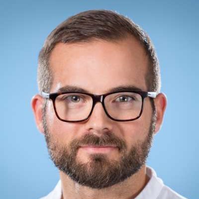 Ein Mann mit Bart und Brille trägt ein weißes Hemd.