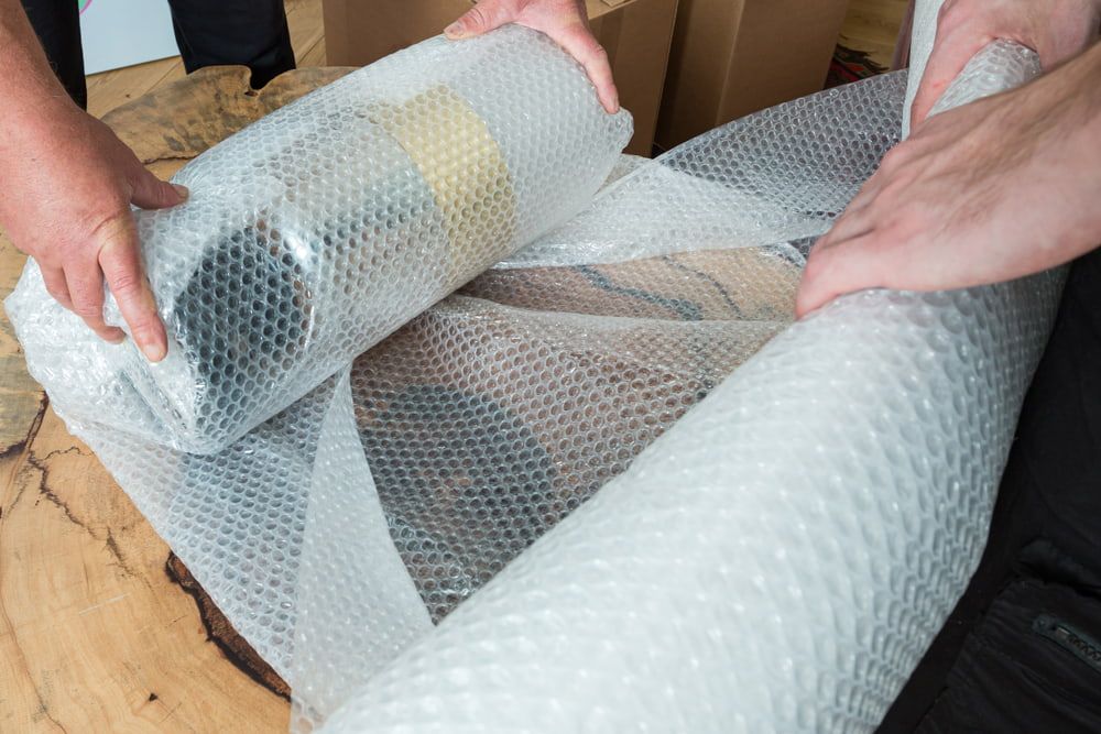 Hands wrapping an object in bubble wrap for protection during moving.