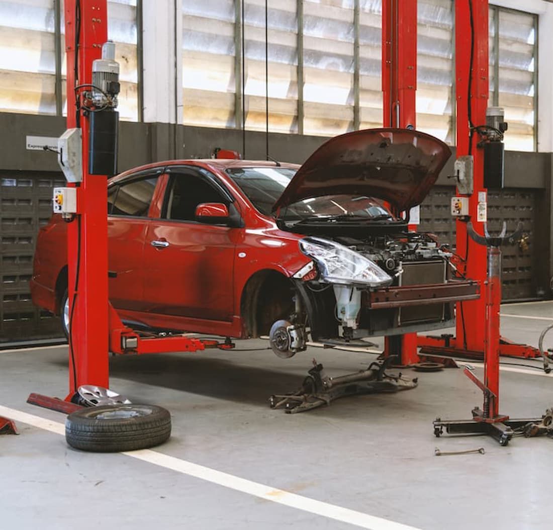 A Red Car with The Hood Open Is on A Lift in A Garage — AJ Automotive Services Bowral in Bowral, NSW