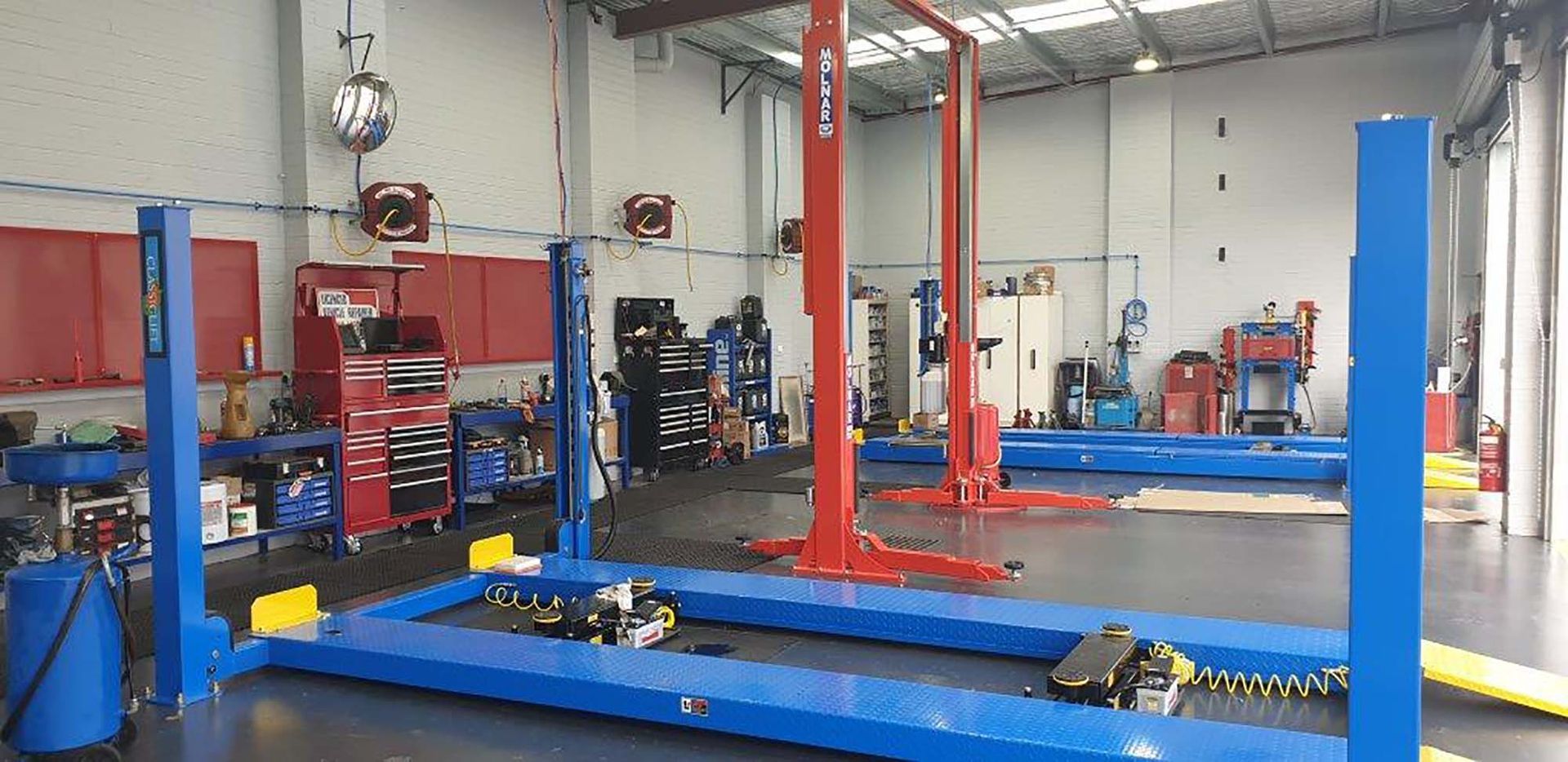 A Garage with Blue Lifts and Red Lifts in It — AJ Automotive Services Bowral in Bowral, NSW