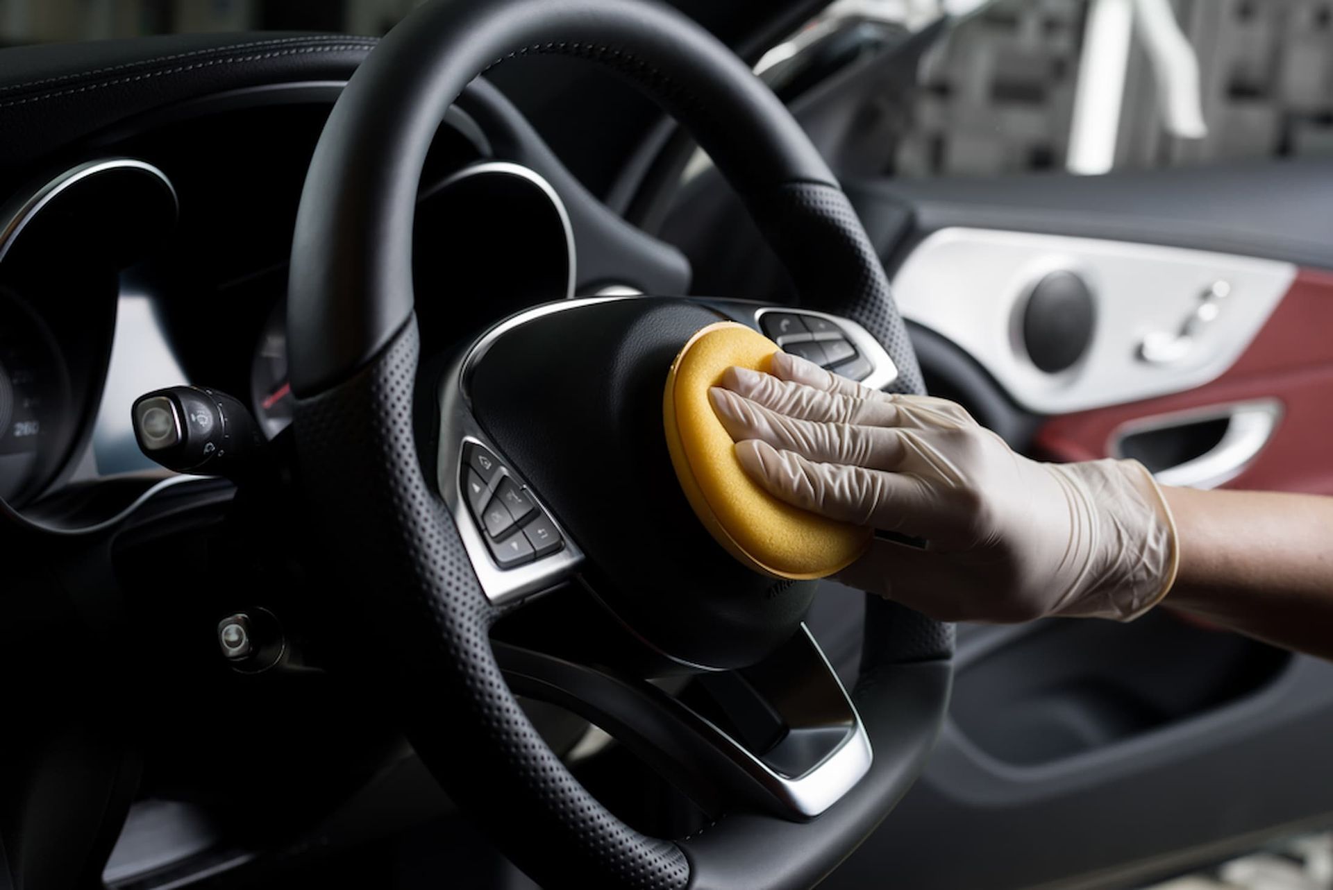 A Person Is Cleaning the Steering Wheel of A Car with A Sponge — AJ Automotive Services Bowral in Bowral, NSW