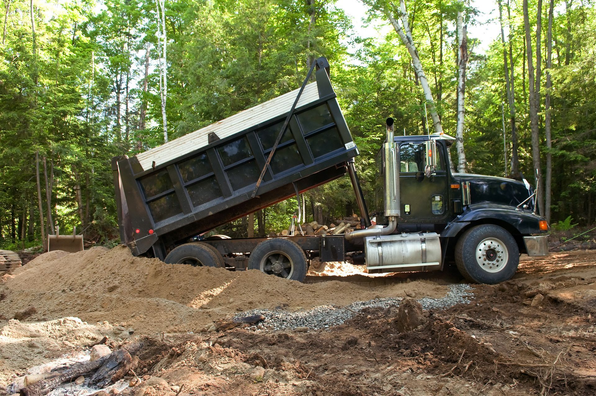 A dump truck from AP Topsoil LLC unloading a premium clay supply in Lafayette, IN, for construction 