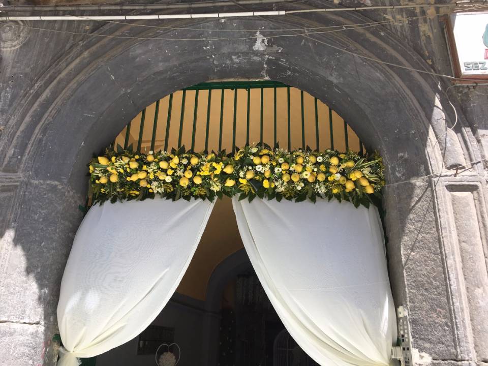 Un portone decorato con fiori gialli e tende bianche