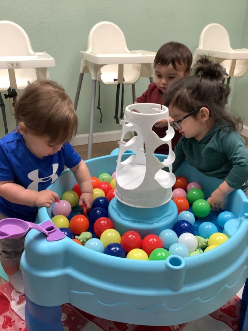 Three young children are playing in a ball pit