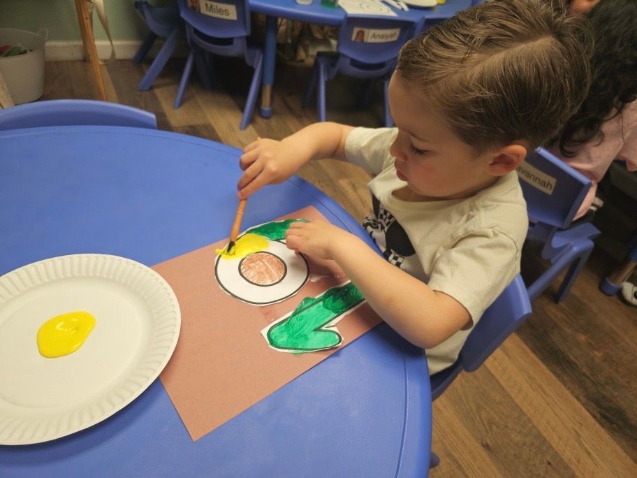 A young boy is painting the number 2 on a piece of paper