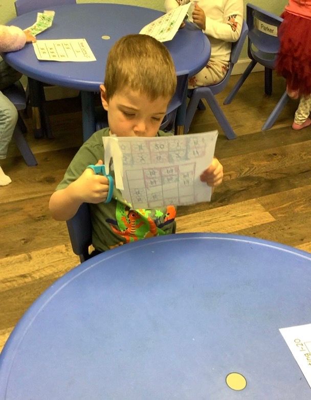 A young boy is cutting a piece of paper with scissors