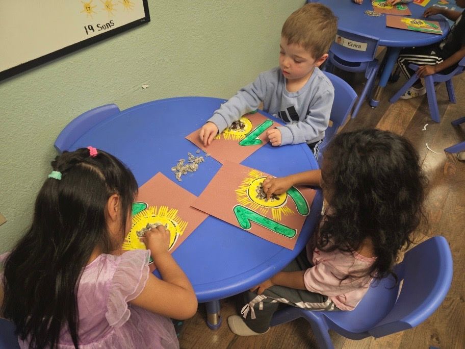 A group of children are sitting at a table making crafts