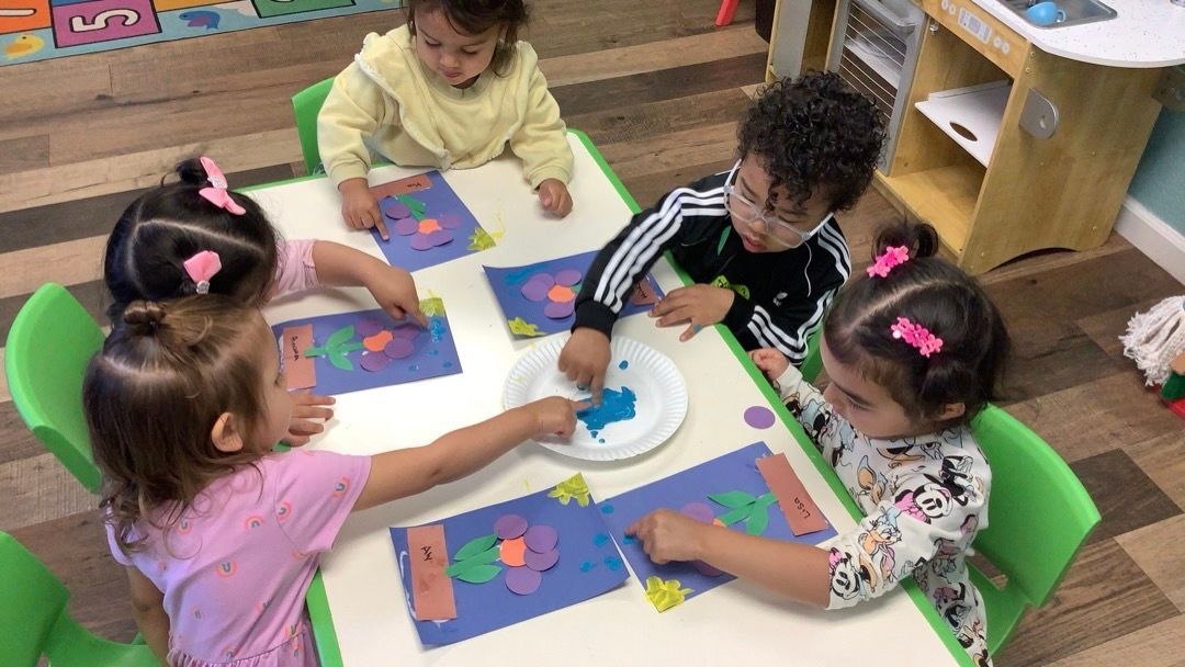 A group of children are sitting at a table making crafts