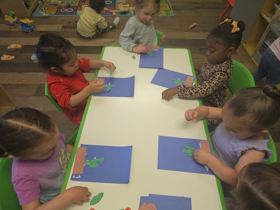 A group of children are sitting at a table making crafts
