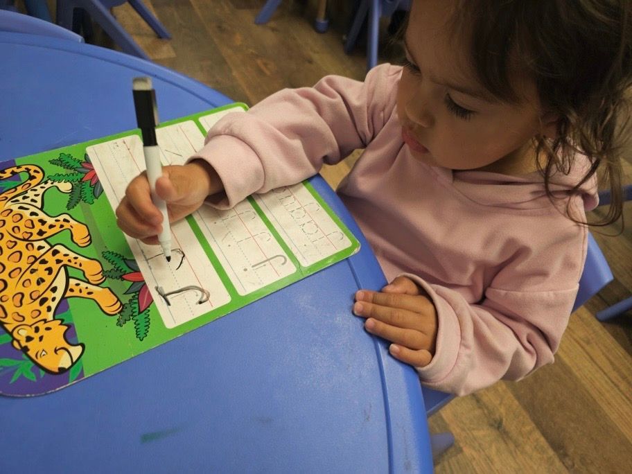 A little girl is writing on a piece of paper with a marker