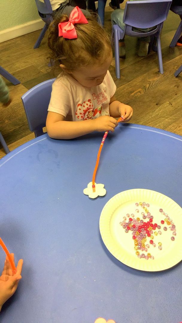 A little girl is sitting at a table with a plate of sprinkles on it