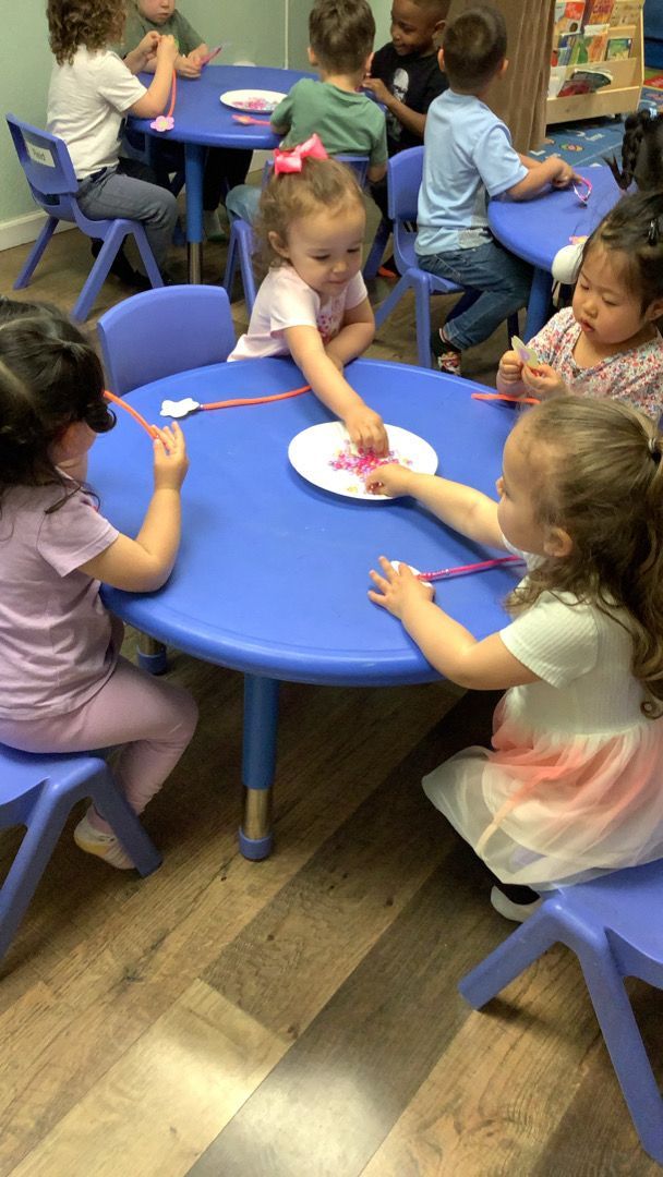 A group of children are sitting around a blue table