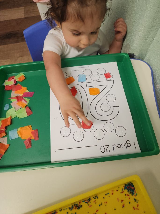 A child is playing with a piece of paper with the number 2 on it
