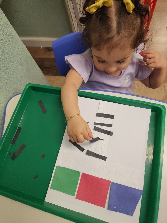 A little girl is playing with a tray of magnets