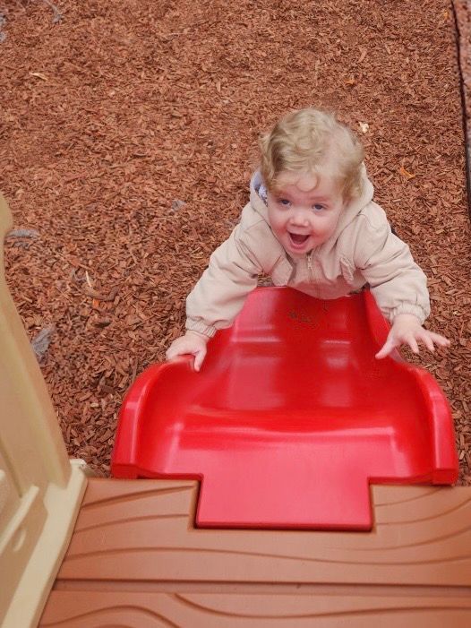 A little girl is playing on a red slide