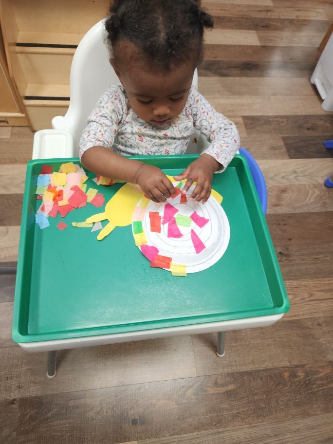 A baby is sitting in a high chair playing with paper plates