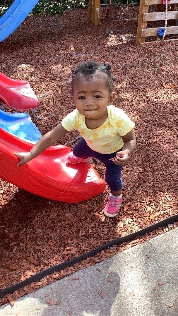 A little girl is playing on a slide at a playground.