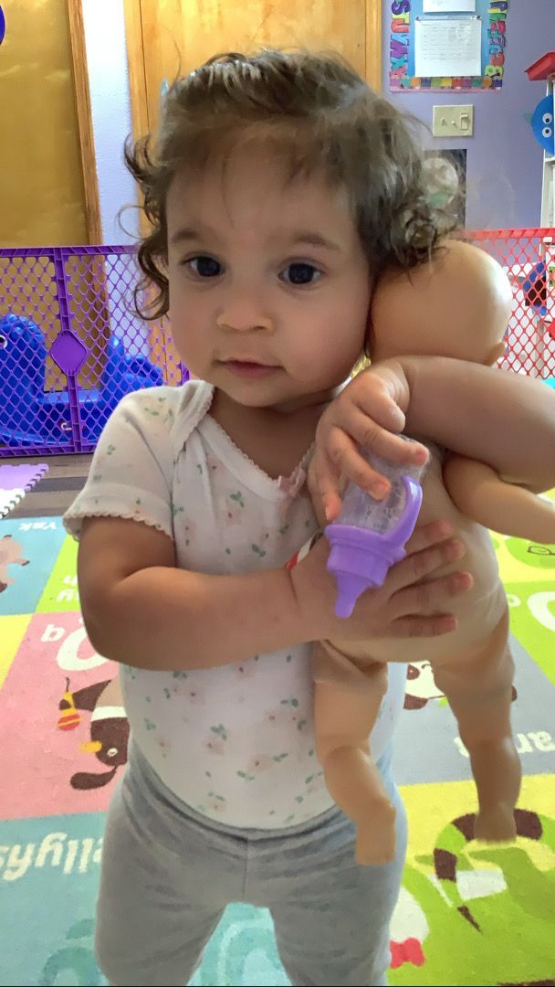 A little girl is holding a baby doll in her arms