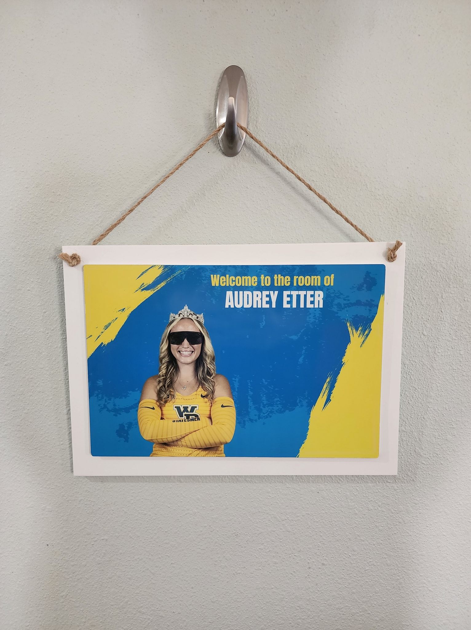 Sign with woman wearing sunglasses, on a wall. Blue and yellow colors.
