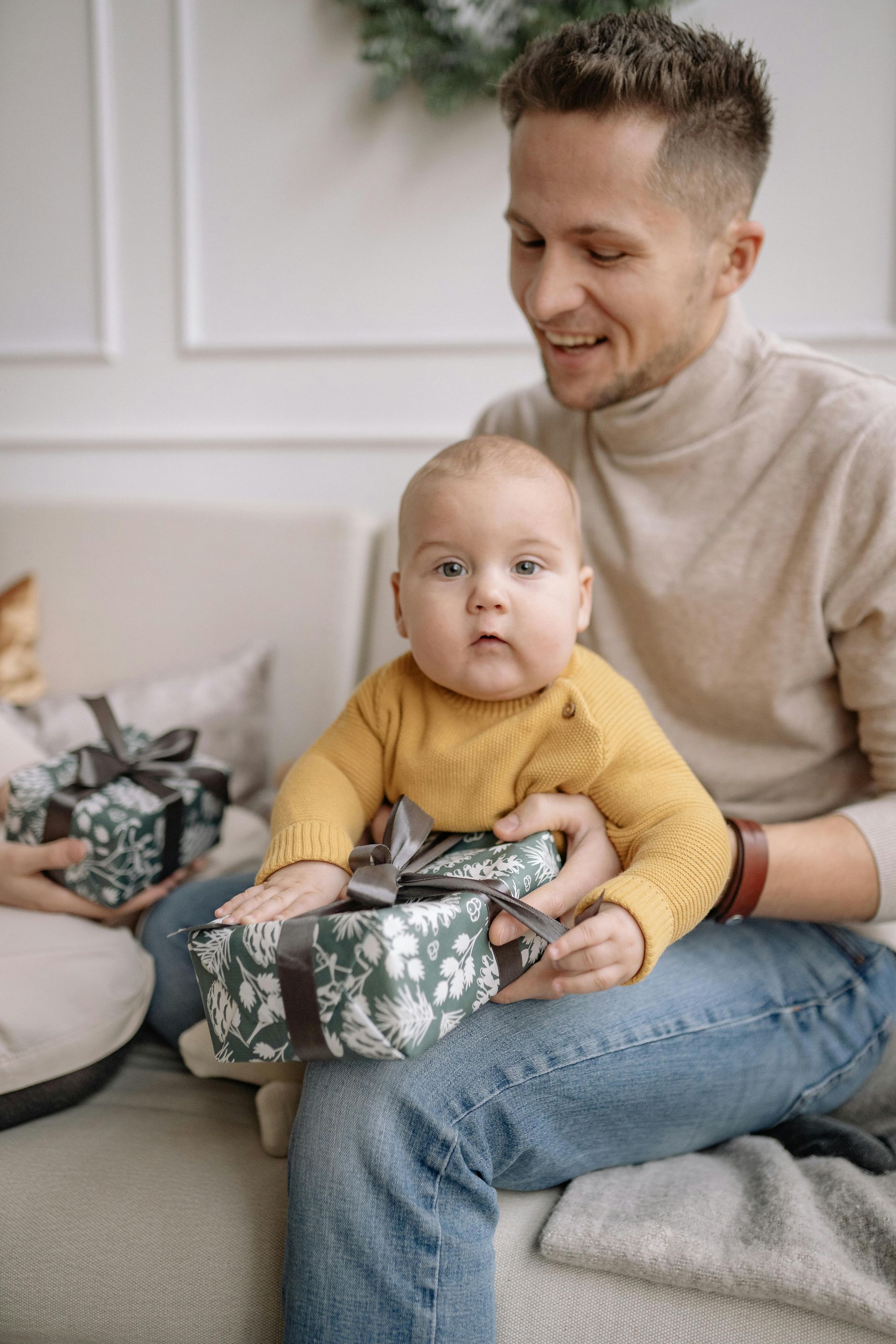 Man holding baby with a gift on his lap; both looking at the camera.