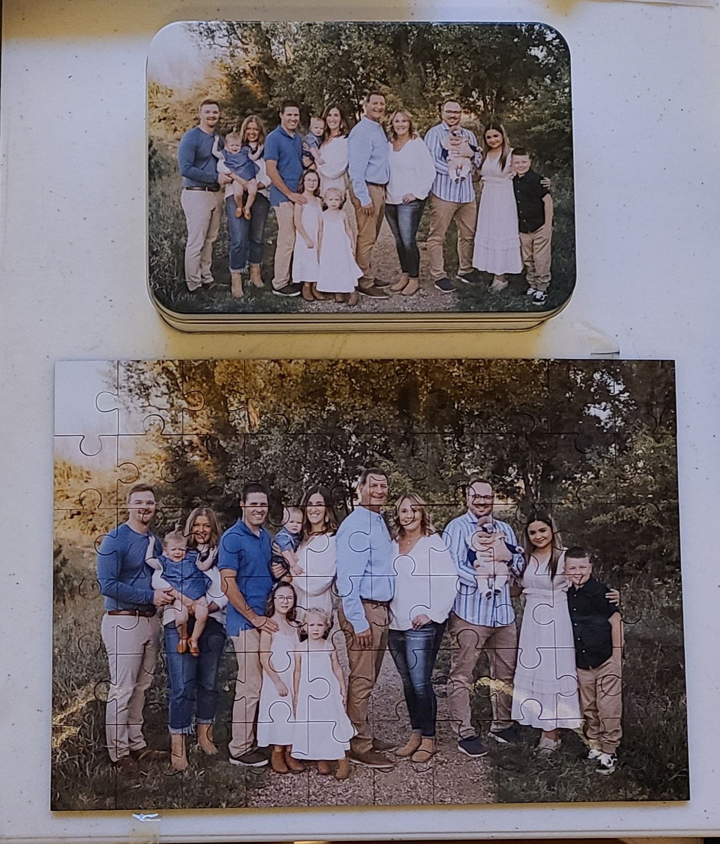 Family photo puzzle, assembled and in pieces, on a wooden surface.