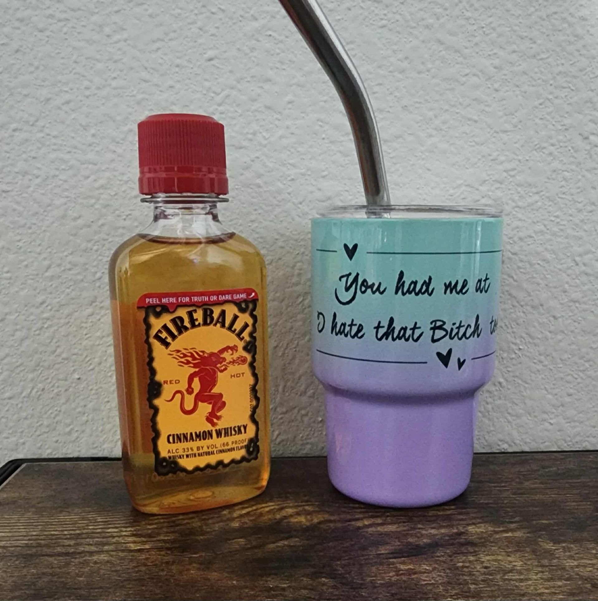 Fireball whiskey bottle next to a tumbler with a straw. The tumbler says 