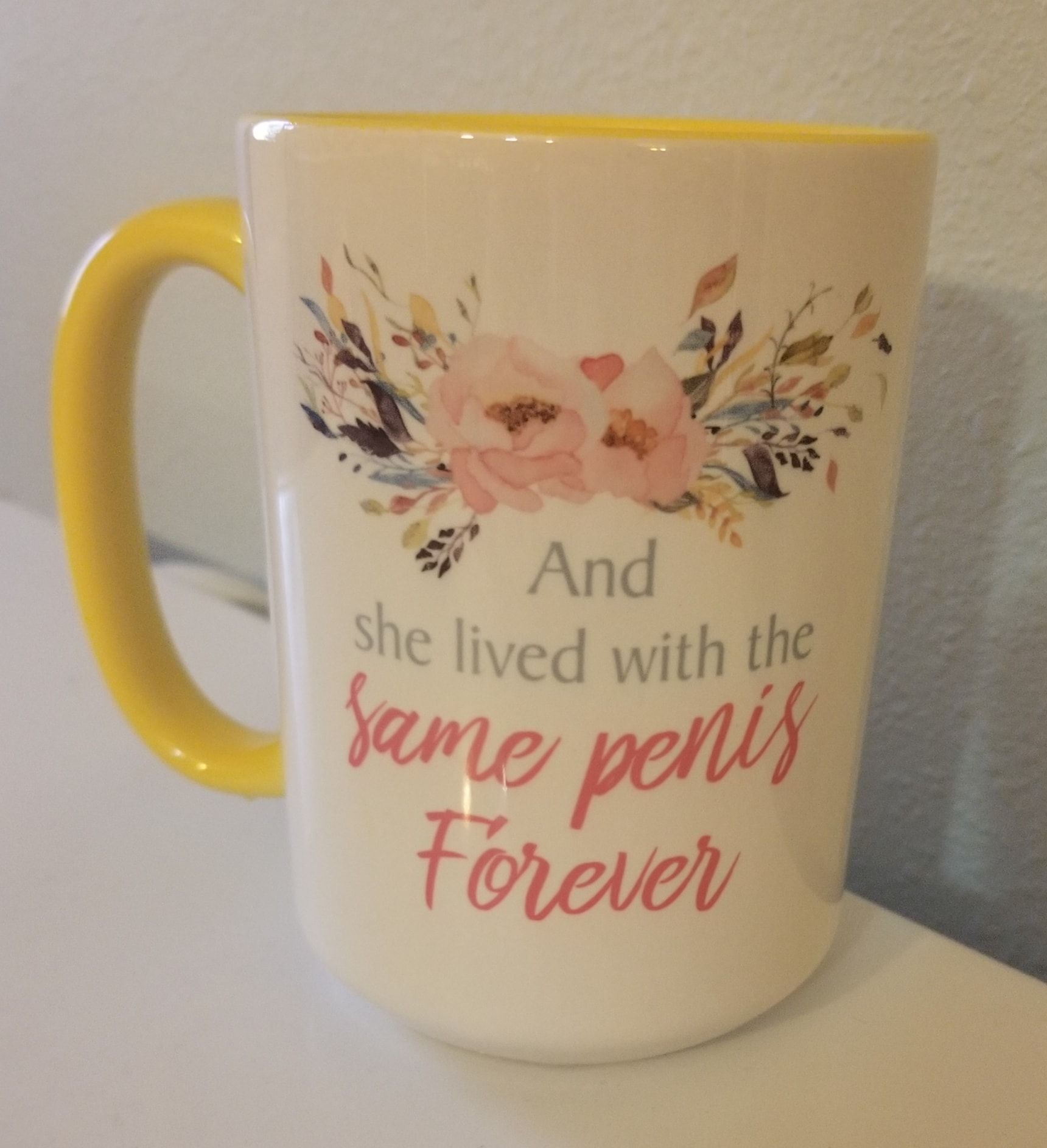 White mug with yellow handle and rim, floral design with text 