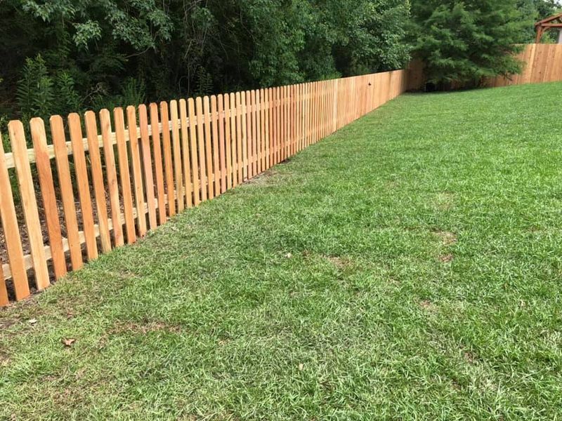 A wooden picket fence surrounds a lush green field.