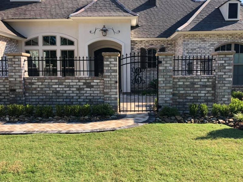 A large white brick house with a wrought iron gate in front of it.
