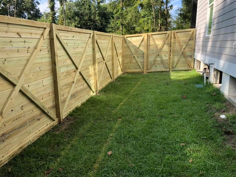 A wooden fence is in the backyard of a house.