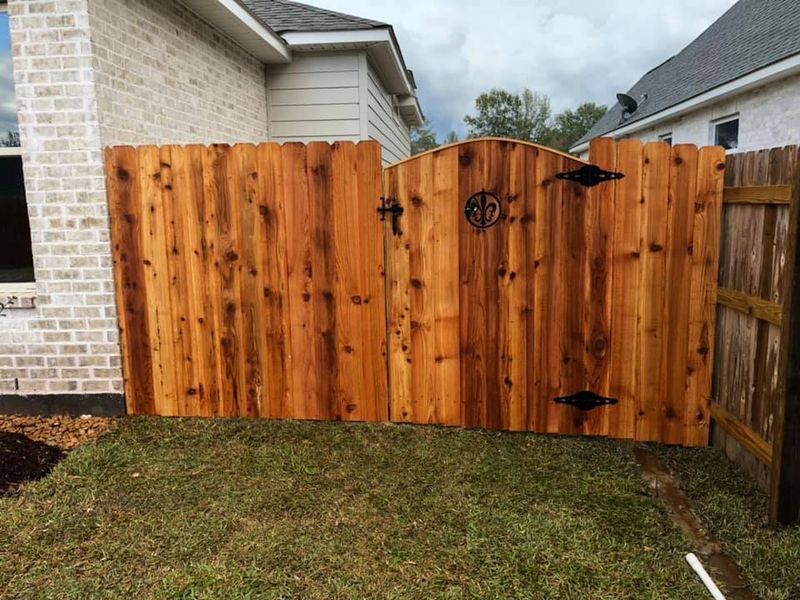 A wooden fence with a gate in the backyard of a house.