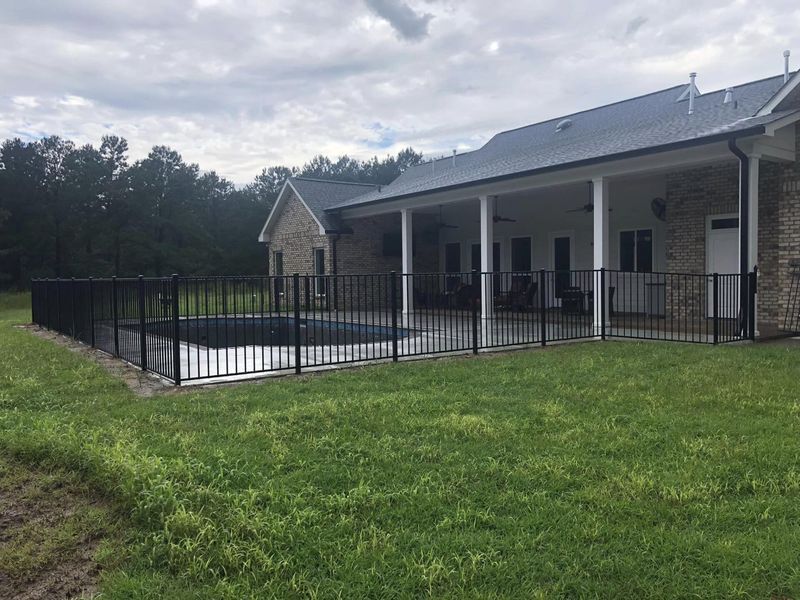 A house with a fence around it and a pool in the backyard.