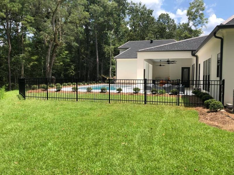 The backyard of a house with a fence and a pool.