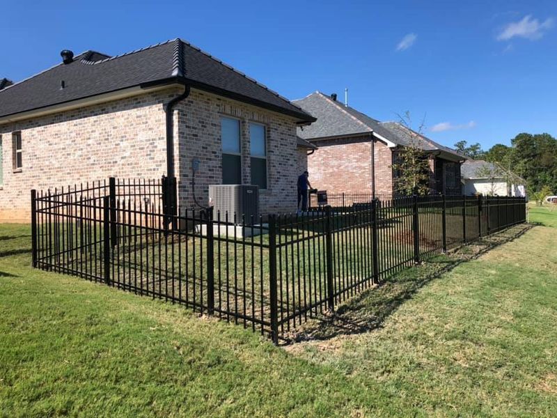 A brick house with a black fence in front of it.