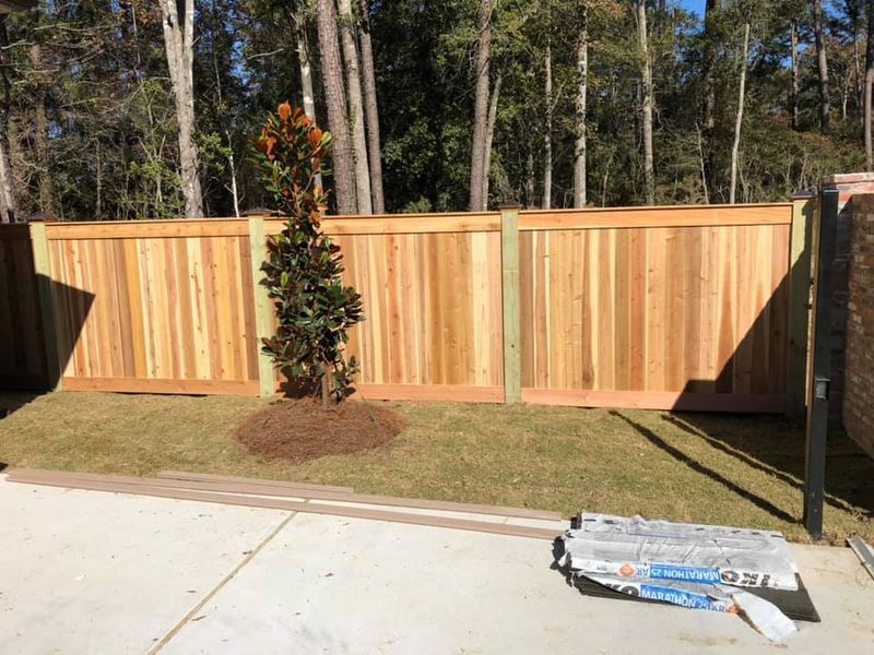 A wooden fence is sitting in the middle of a lush green yard.