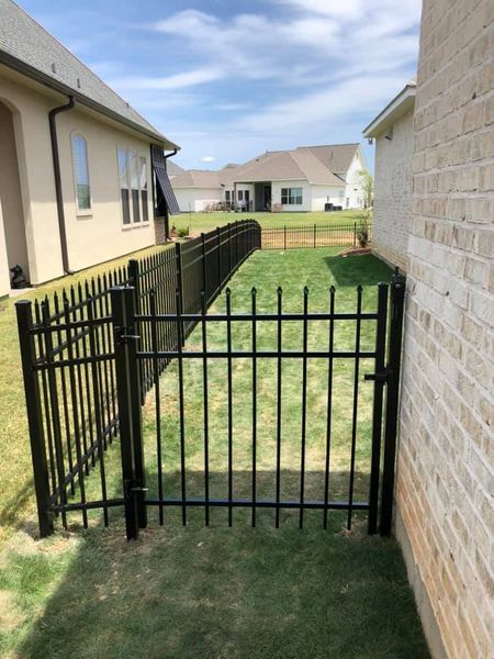A black fence with a gate leading to a house