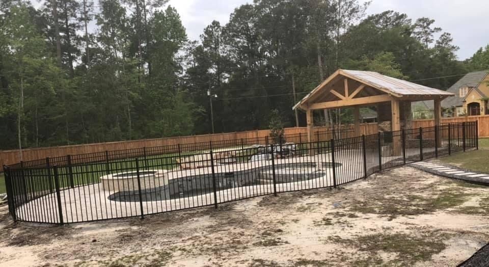 A metal fence surrounds a swimming pool in a backyard.