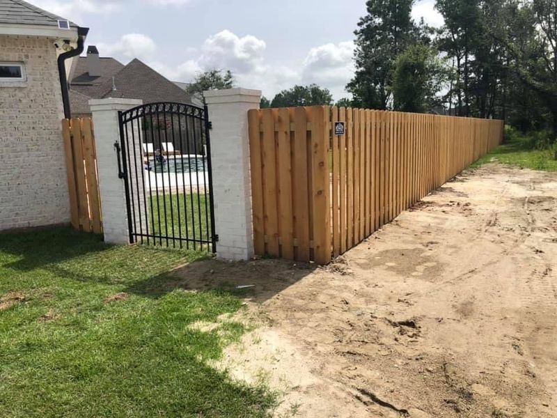 A wooden fence with a gate in front of a house.