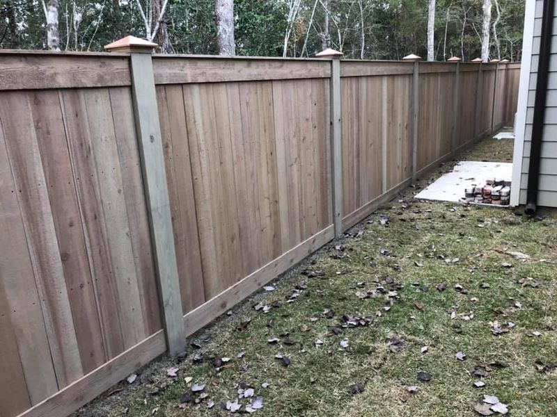 A wooden fence is in the backyard of a house.