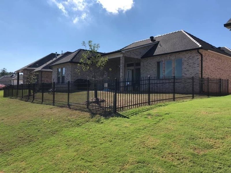 A brick house with a black fence in front of it.