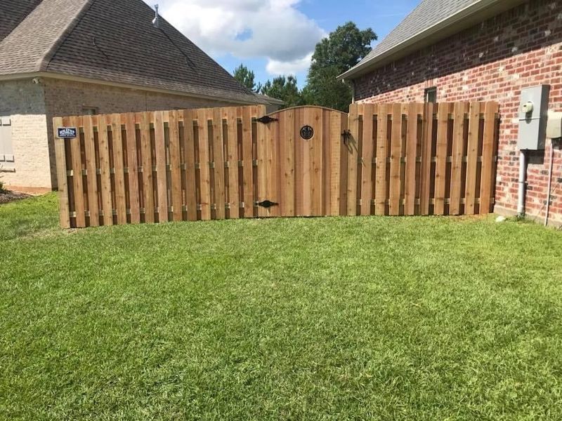 A wooden fence with a gate in the backyard of a house.