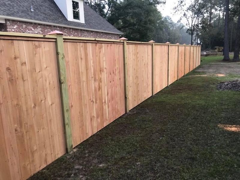 A wooden fence is sitting in the grass in front of a house.