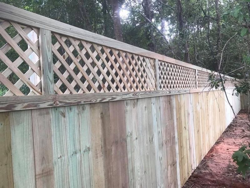 A wooden fence with a lattice on the side of it.