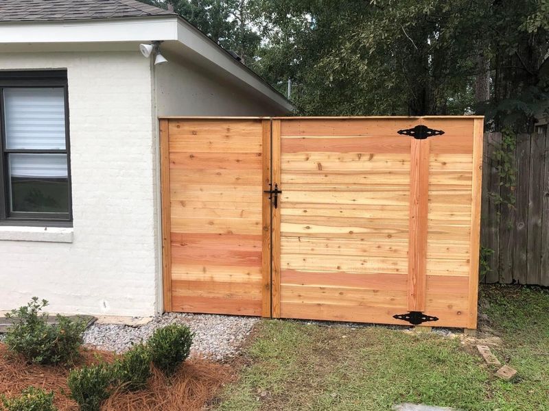 A wooden fence is sitting in front of a white house.