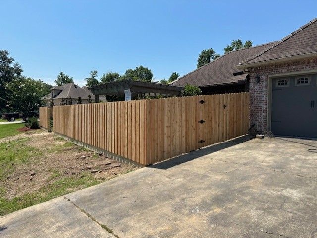 A wooden fence is sitting in front of a house next to a garage.
