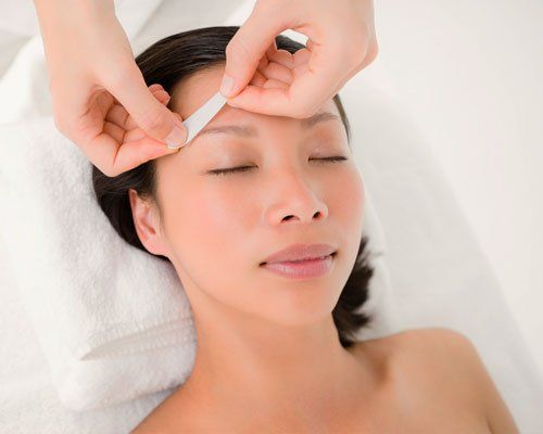 A woman is getting her eyebrows waxed at a beauty salon.