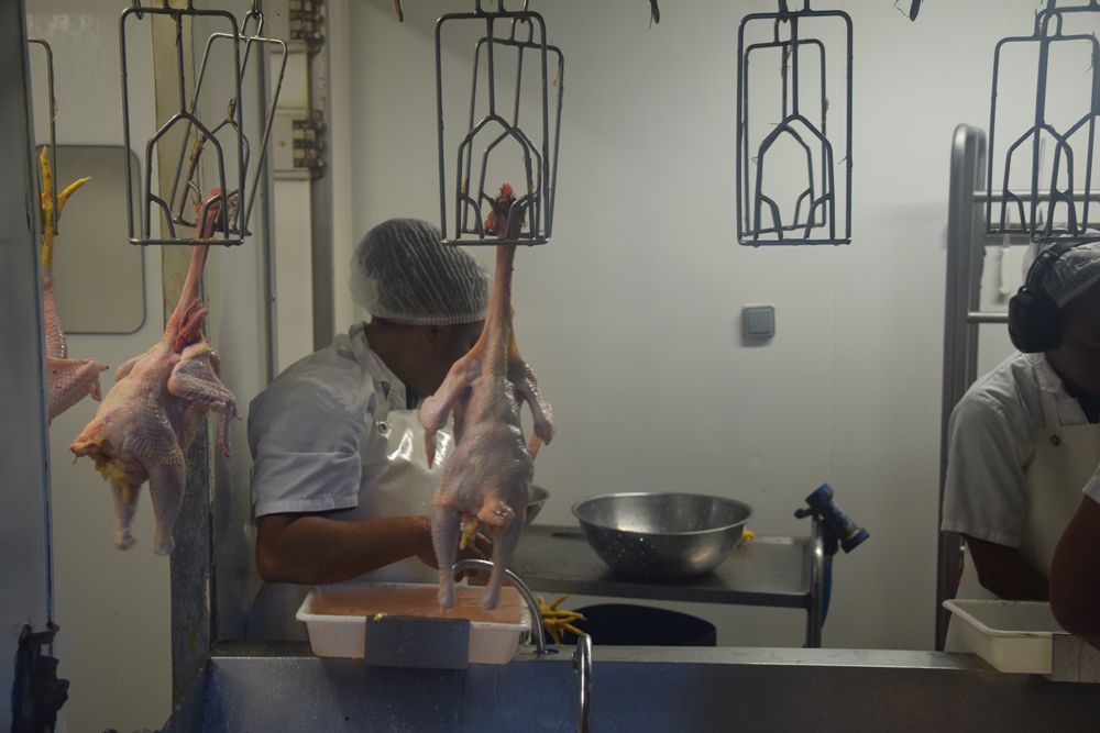 Un homme coupe un poulet dans une boucherie